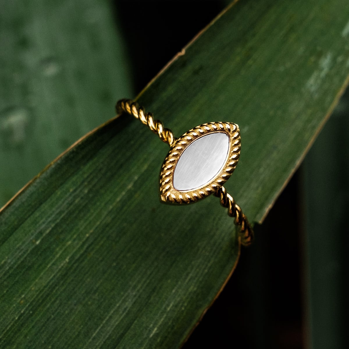 Anello "Visual Ring" con accenti bianchi e oro con un design elegante e contorto.
