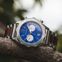 "Osprey watch featuring a blue dial and silver accents with a wooden and metal band for a stylish look."