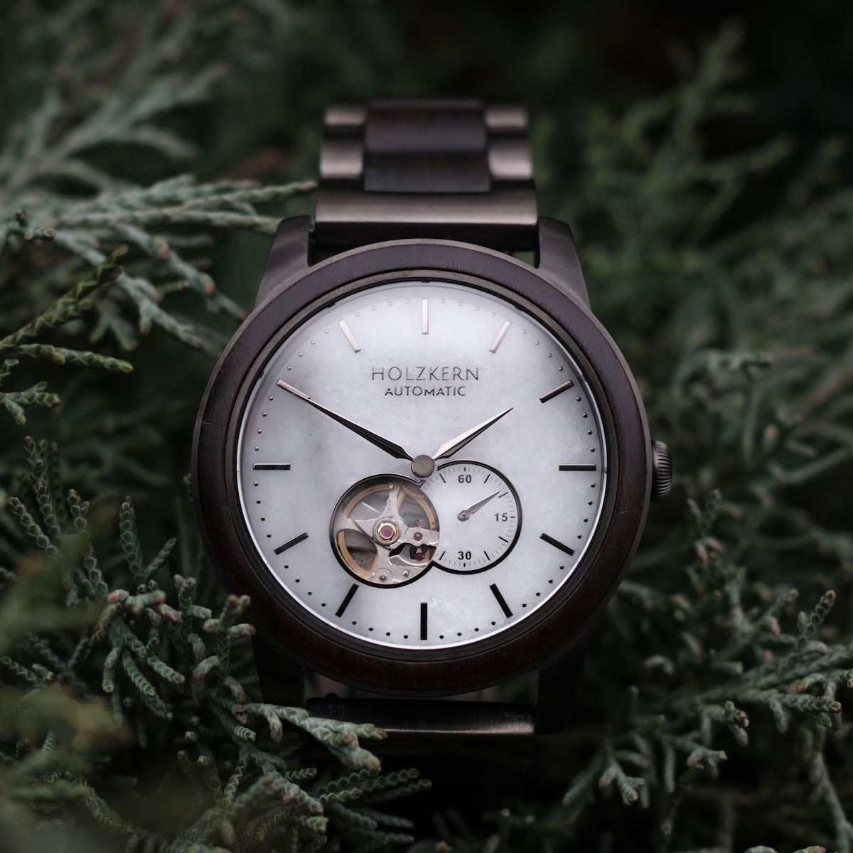 Orologio "Manhattan" con un sofisticato disegno in legno di acero e marmo su uno sfondo verde rigoglioso.