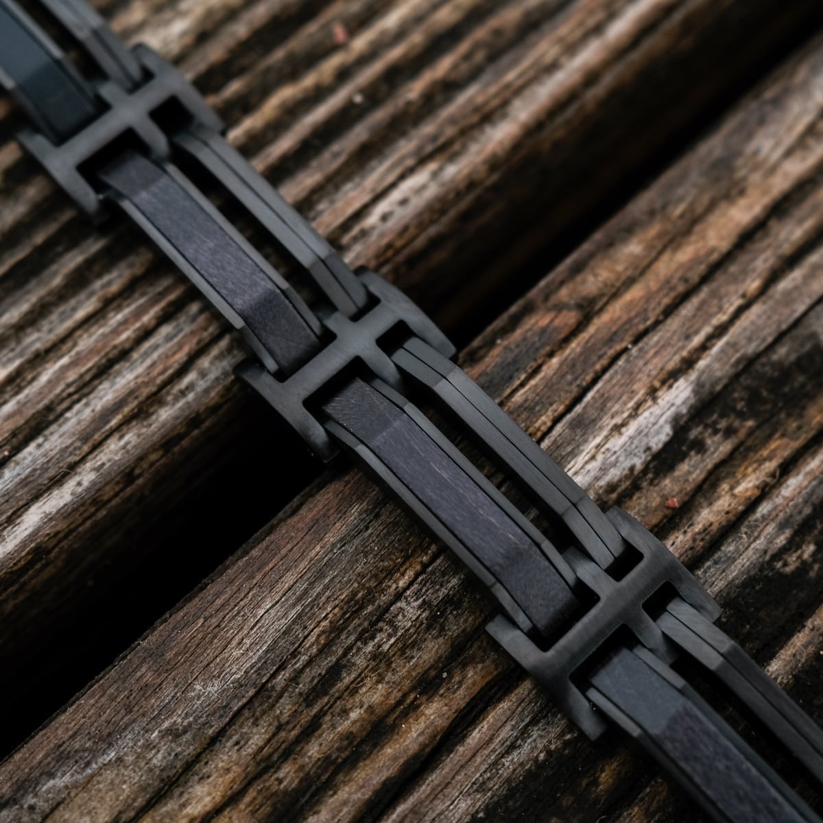 Bracciale "Staccato", con un elegante acero e un design nero su una superficie in legno strutturato.