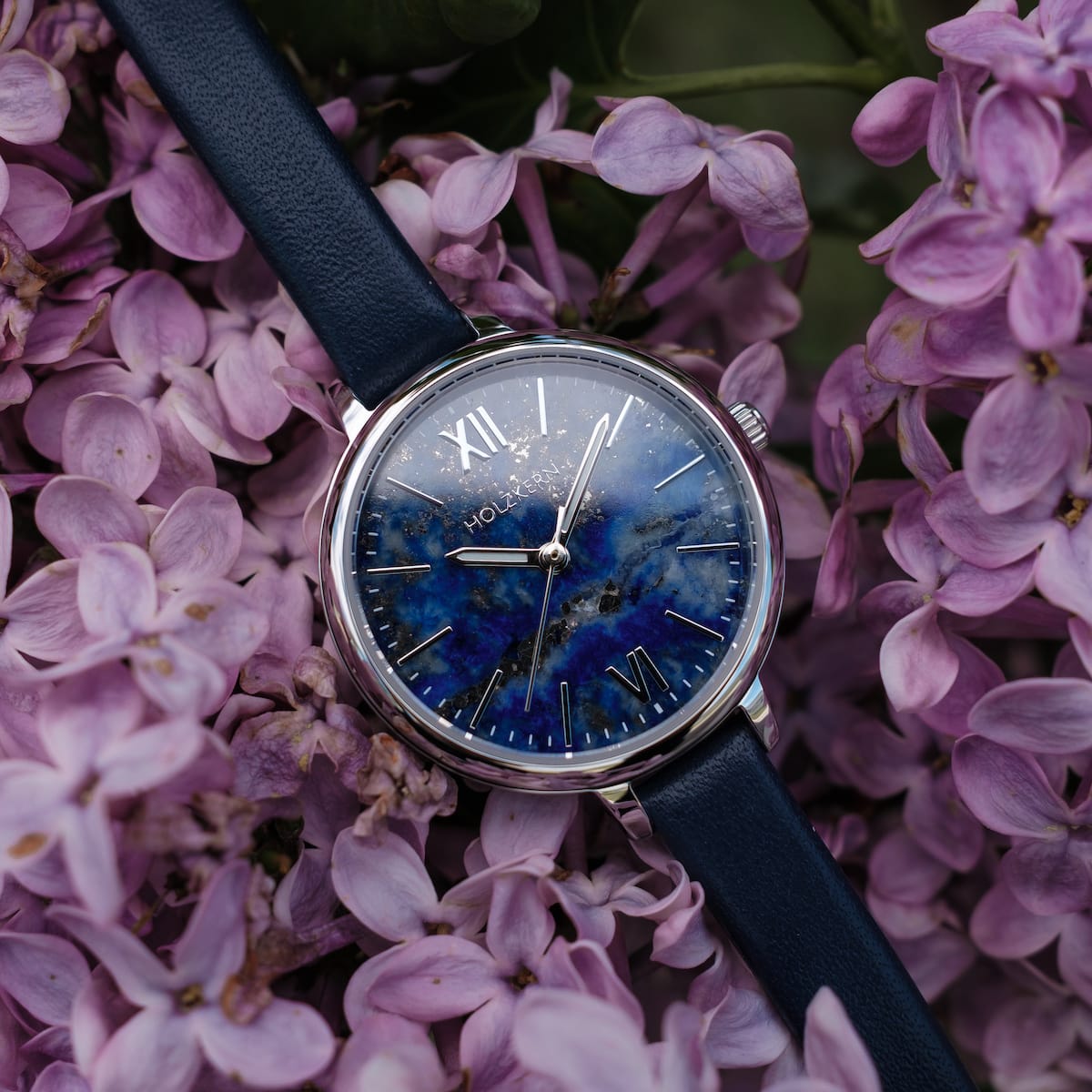 "Teresa" watch with lapis lazuli face and silver accents, surrounded by purple flowers.