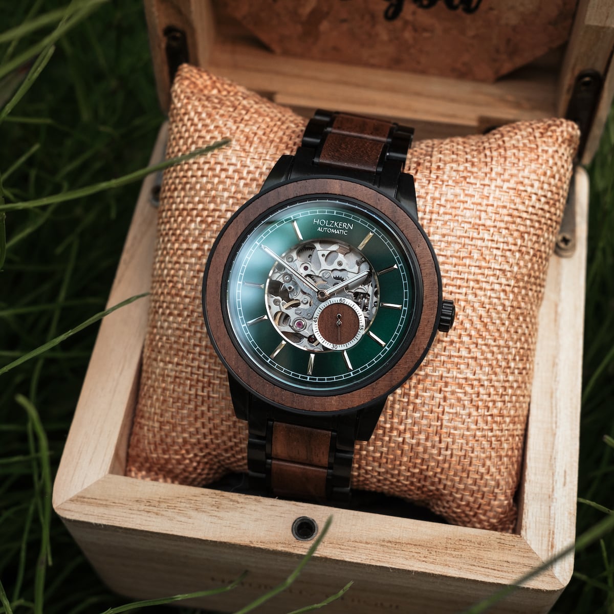 Orologio "Sigiriya" con cassa in noce e design meccanico intricato in una scatola in legno rustico.