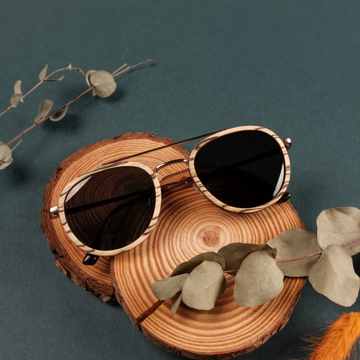 Occhiali da sole "The Risky" con cornice in zebrawood e accenti in oro opaco su uno sfondo rustico.