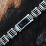 "Adagio" watch featuring a blue marble face and silver links on a rustic wood background.