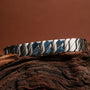 Bracciale "Baritone" in sodalite e argento con un design moderno e strutturato su uno sfondo rustico.