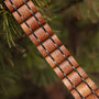 "Grandezza, wooden bracelet featuring a mahogany and gray design on a natural background."