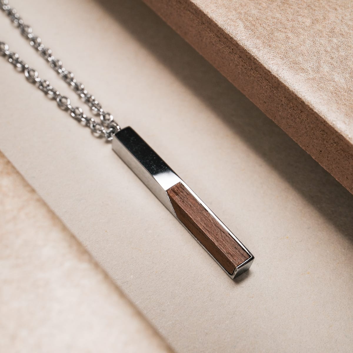 "Campania Necklace", a stylish necklace featuring walnut and silver elements with a sleek, modern design.