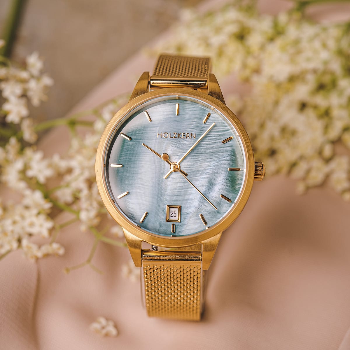 "Talamanca", elegante orologio con quadrante e accenti d'oro, impostato su uno sfondo floreale.