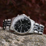 "The Observant watch, featuring a sleek black dial and stainless steel bracelet, exudes a modern and elegant style."