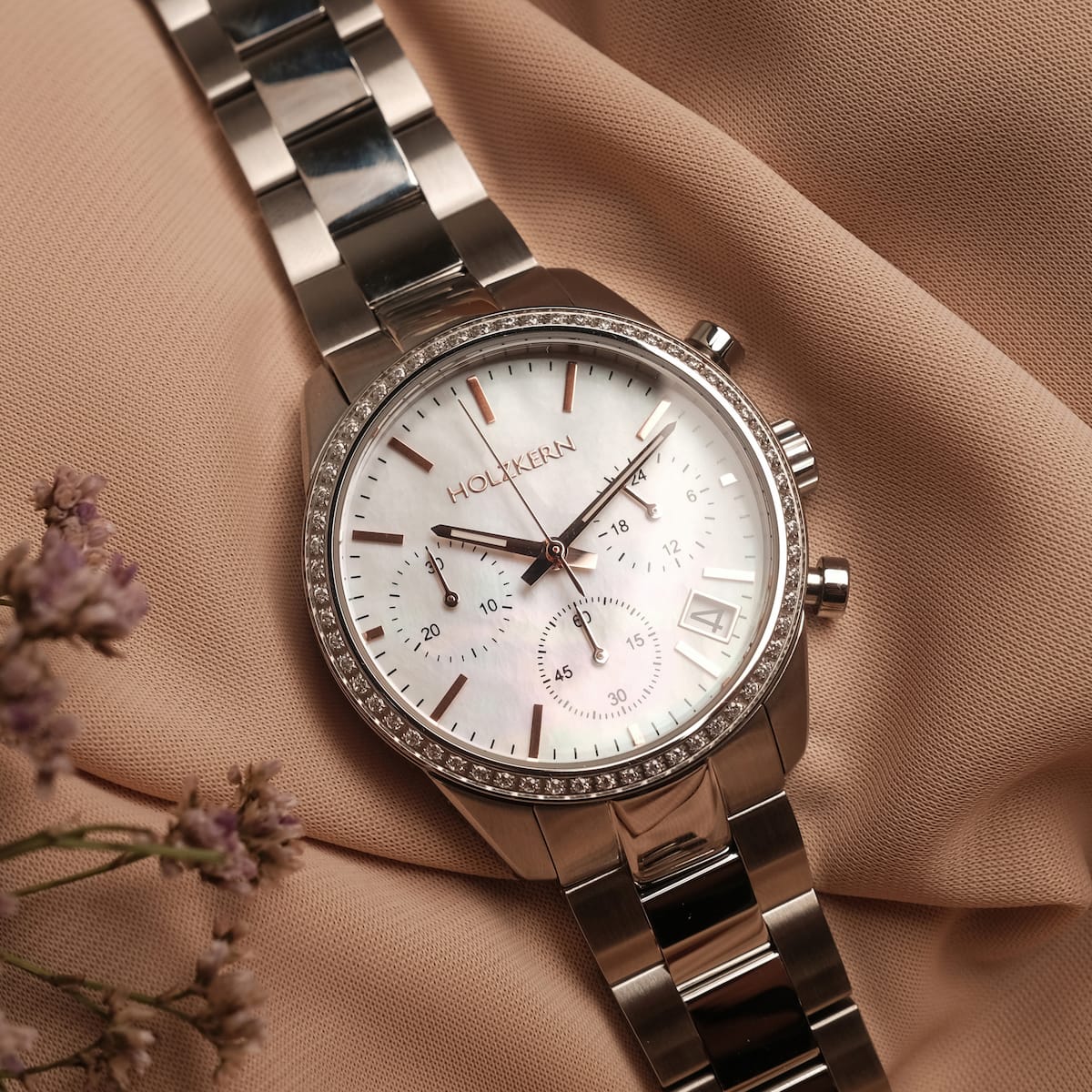 "The Balanced", un orologio elegante con materiali in argento e nacre su uno sfondo morbido.