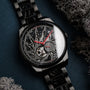 "Pacemaker watch with a marble style, featuring intricate detailing and red accents on a dark metal bracelet."