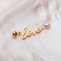 "Love-Charm" fascino con oro lettering e accenti perla su uno stile di fondo morbido.