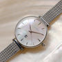 "Piccolo" watch features a nacre dial and silver mesh band, highlighting its elegant design.