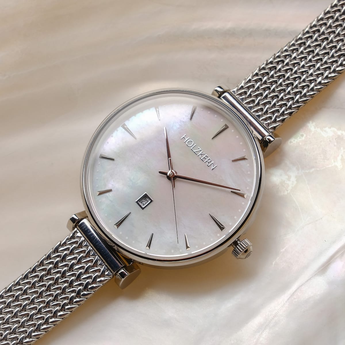 "Piccolo" watch features a nacre dial and silver mesh band, highlighting its elegant design.