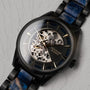 Orologio da polso "Vredefort" con un design in marmo e nero, caratterizzato da un quadrante scheletrico intricato e accenti azzurri.