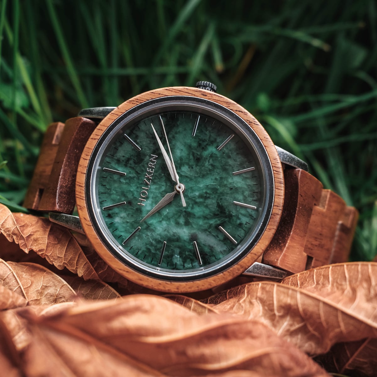 "Bob" watch featuring a koa wood band and marble green face, displayed on autumn leaves and grass backdrop.