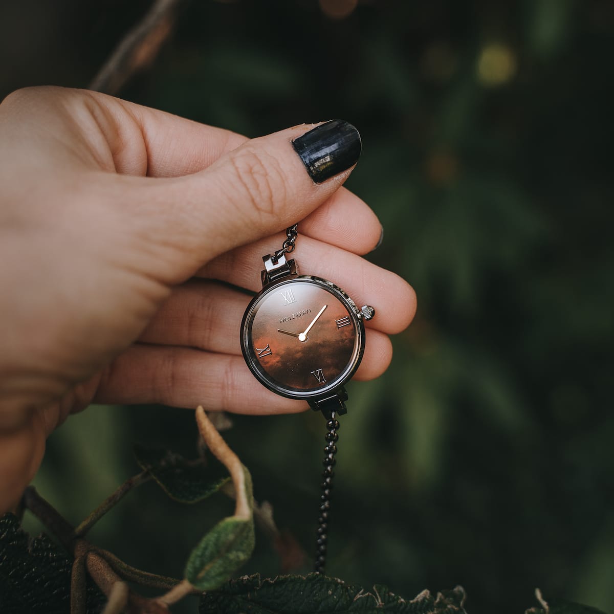 Orologio "Élisa" con finitura grigio scuro e nacre, eroe in mano su uno sfondo naturale.