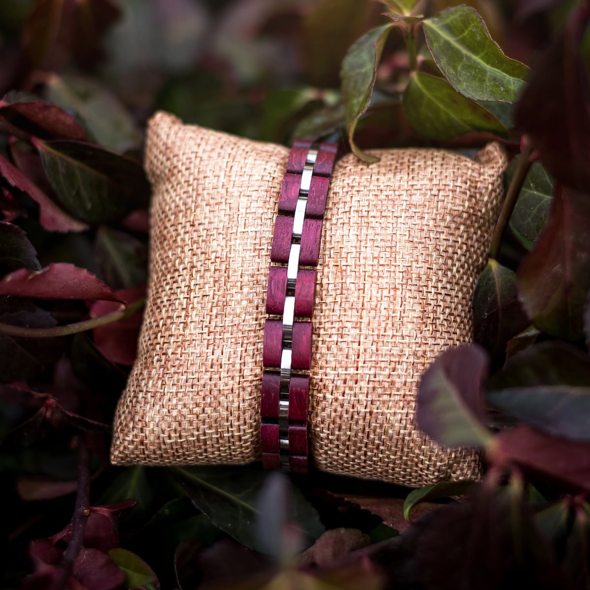 Bracciale "Fantasia" con accenti amaranto e argento, con un design intrecciato su uno sfondo naturale.