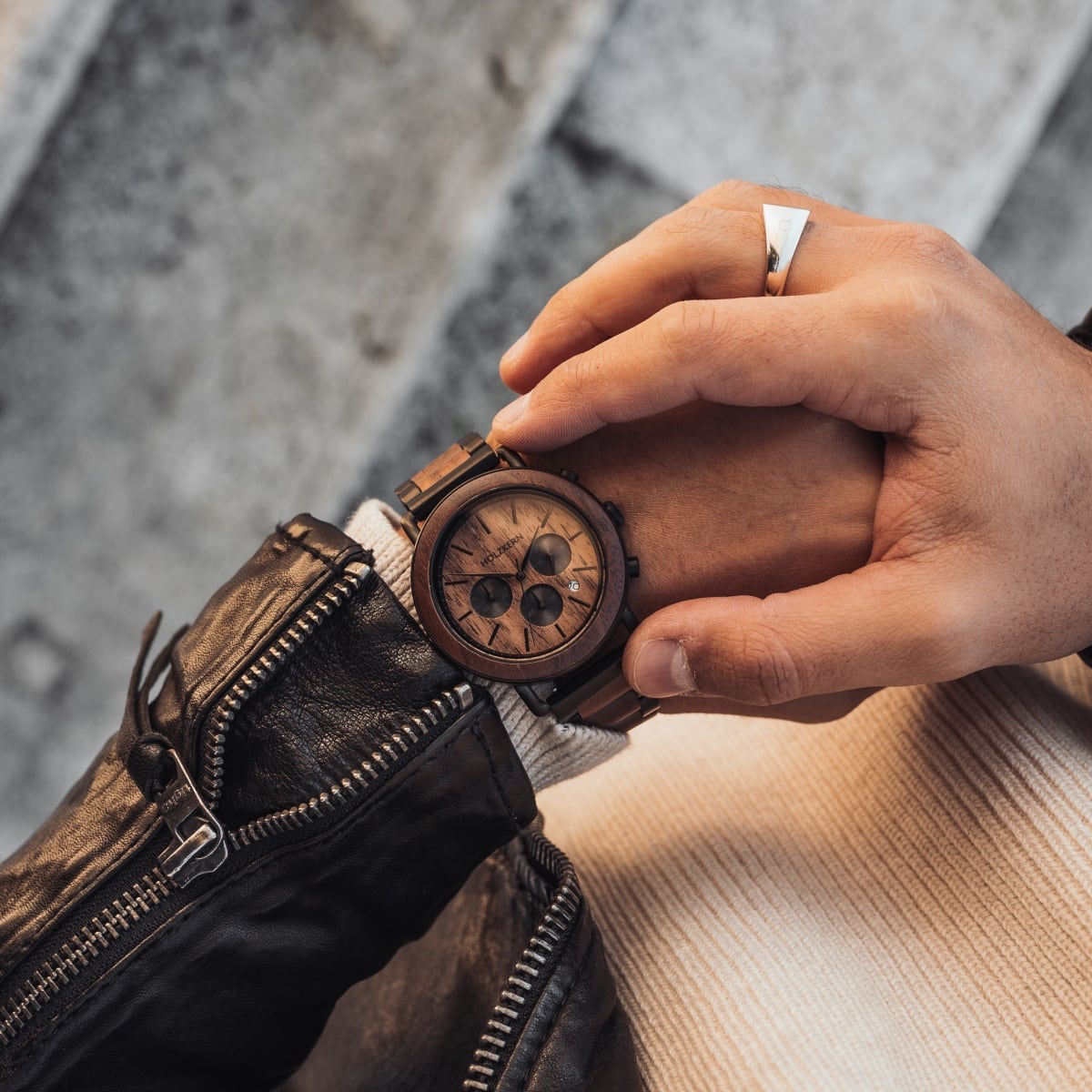 "Dusk" watch, featuring a walnut and black design, held by a person wearing a leather jacket.