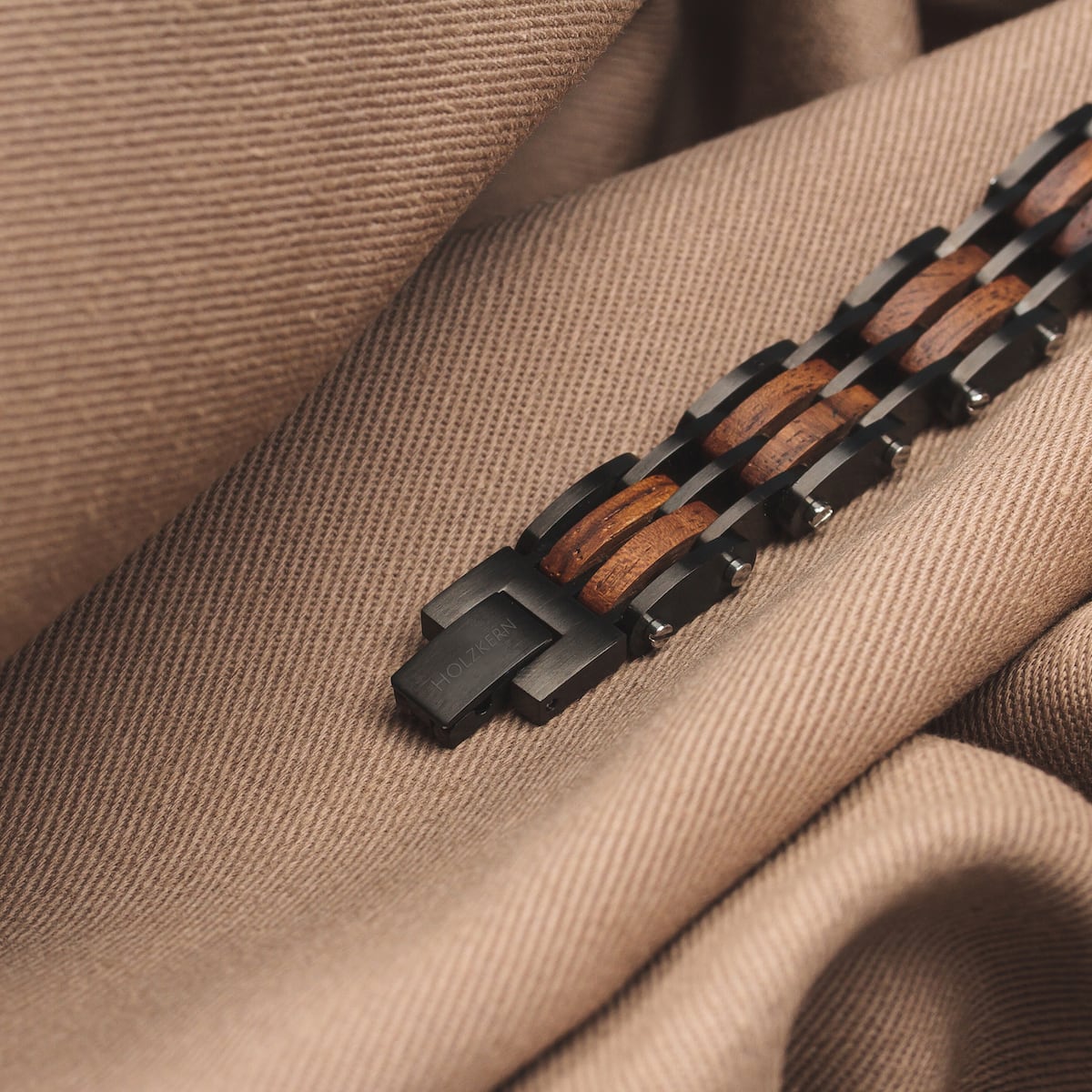 "Adagio" bracelet in walnut/gray, featuring a sleek, natural design on a textured fabric background.
