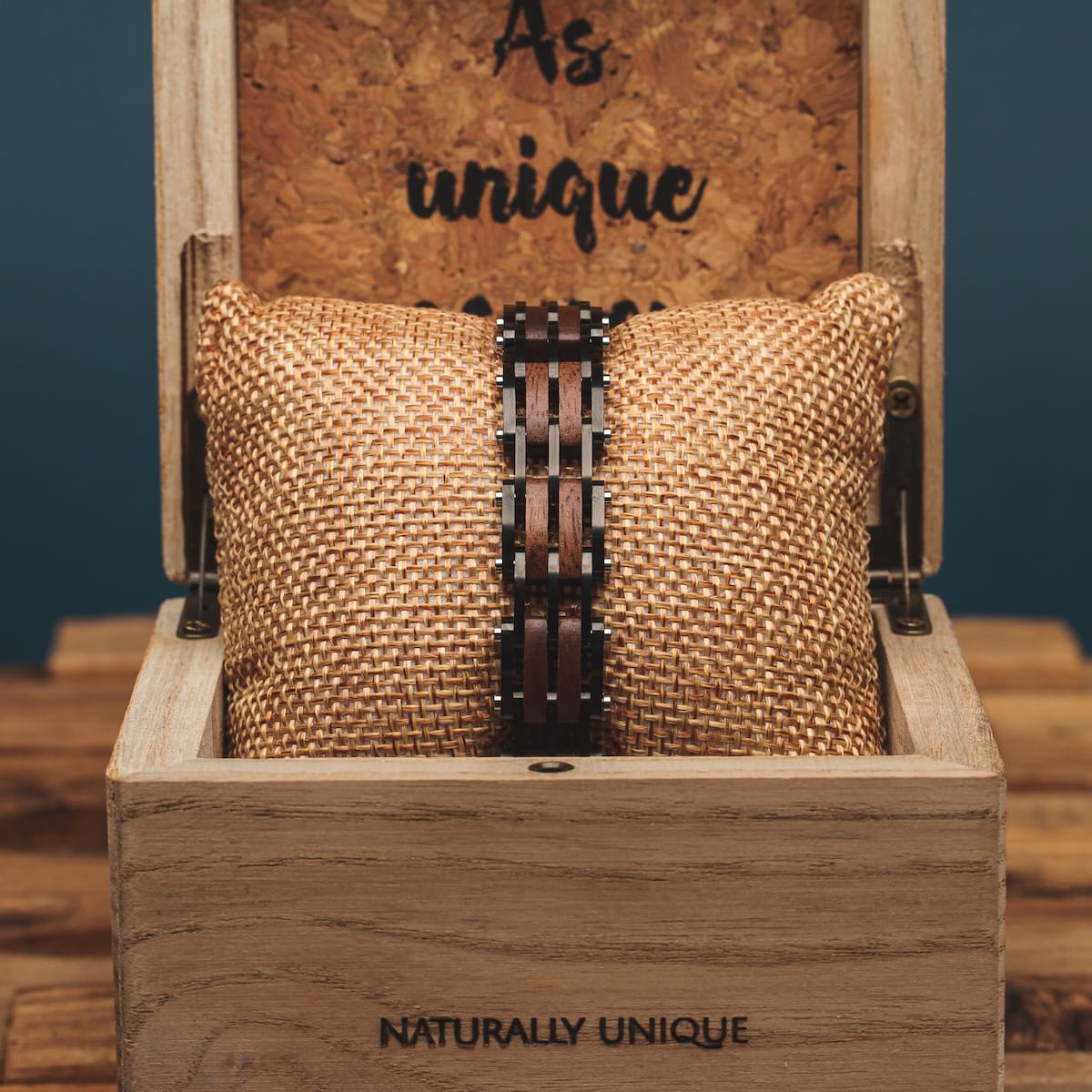 "Adagio" wrist accessory in walnut and gray, showcased in a rustic woven display.