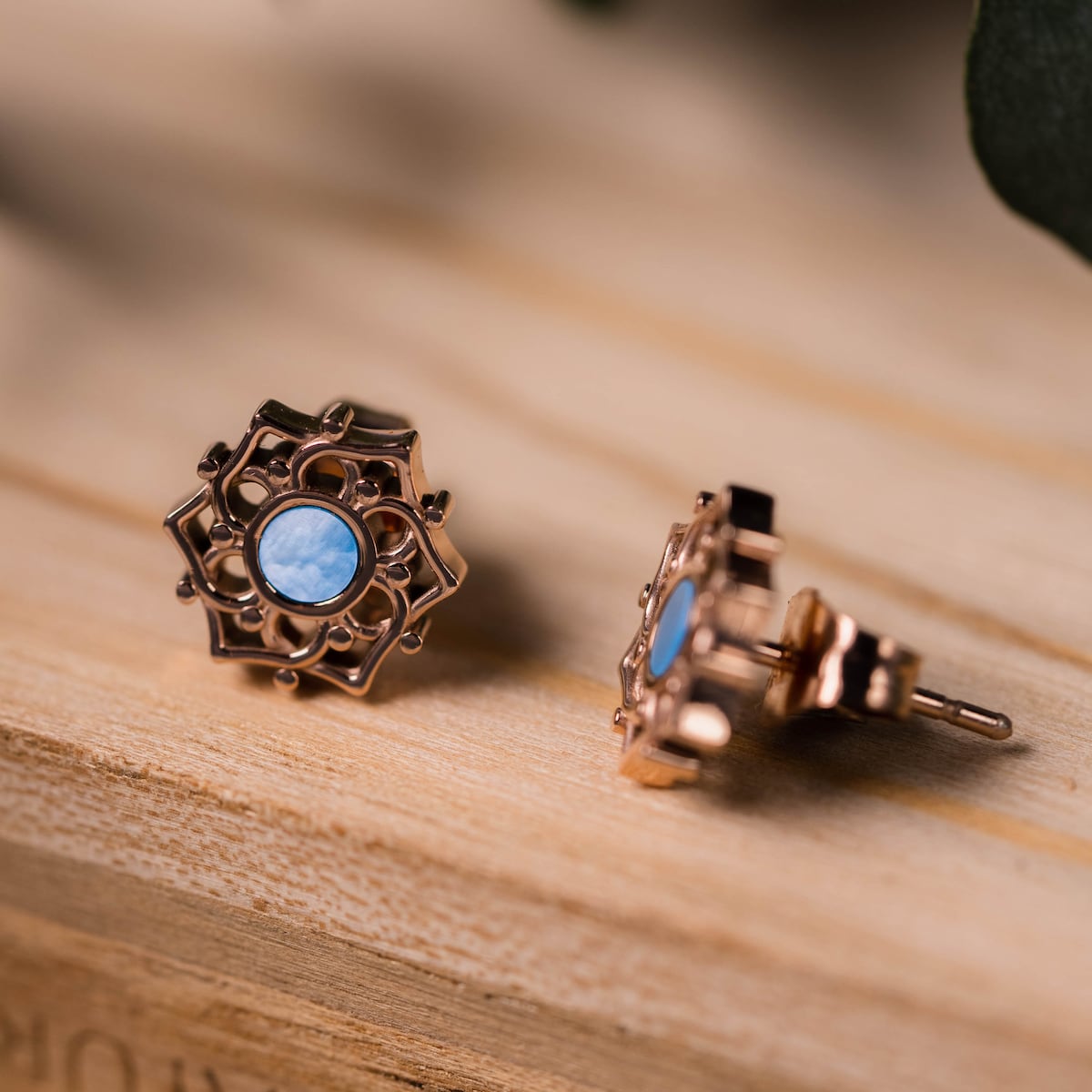 "Composition Earrings" earrings in blue nacre and rose gold, showcasing an intricate and elegant design on a wooden surface.