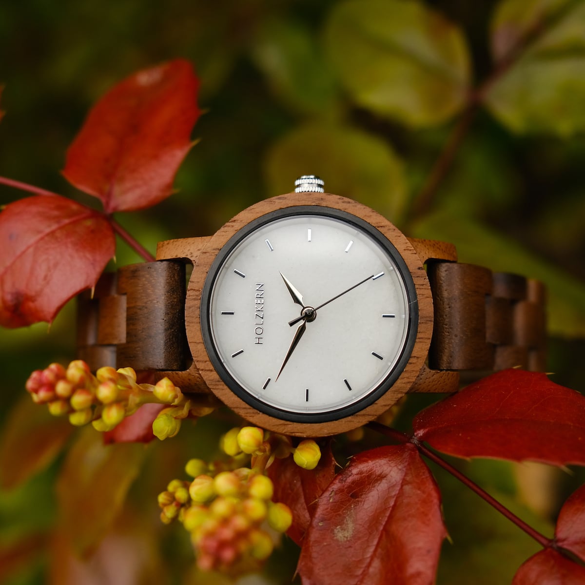 Orologio d'aria, caratterizzato da un design in legno di noce e marmo, elegantemente ambientato su uno sfondo di vivaci foglie autunnali.