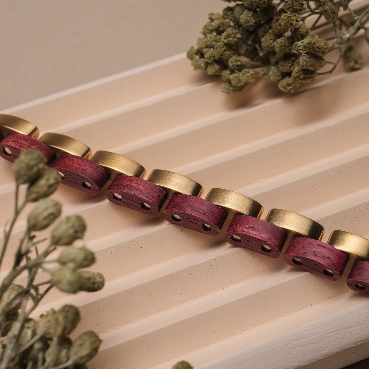 "Duet", a stylish bracelet featuring amaranth wood and gold accents, elegantly displayed against a textured background.