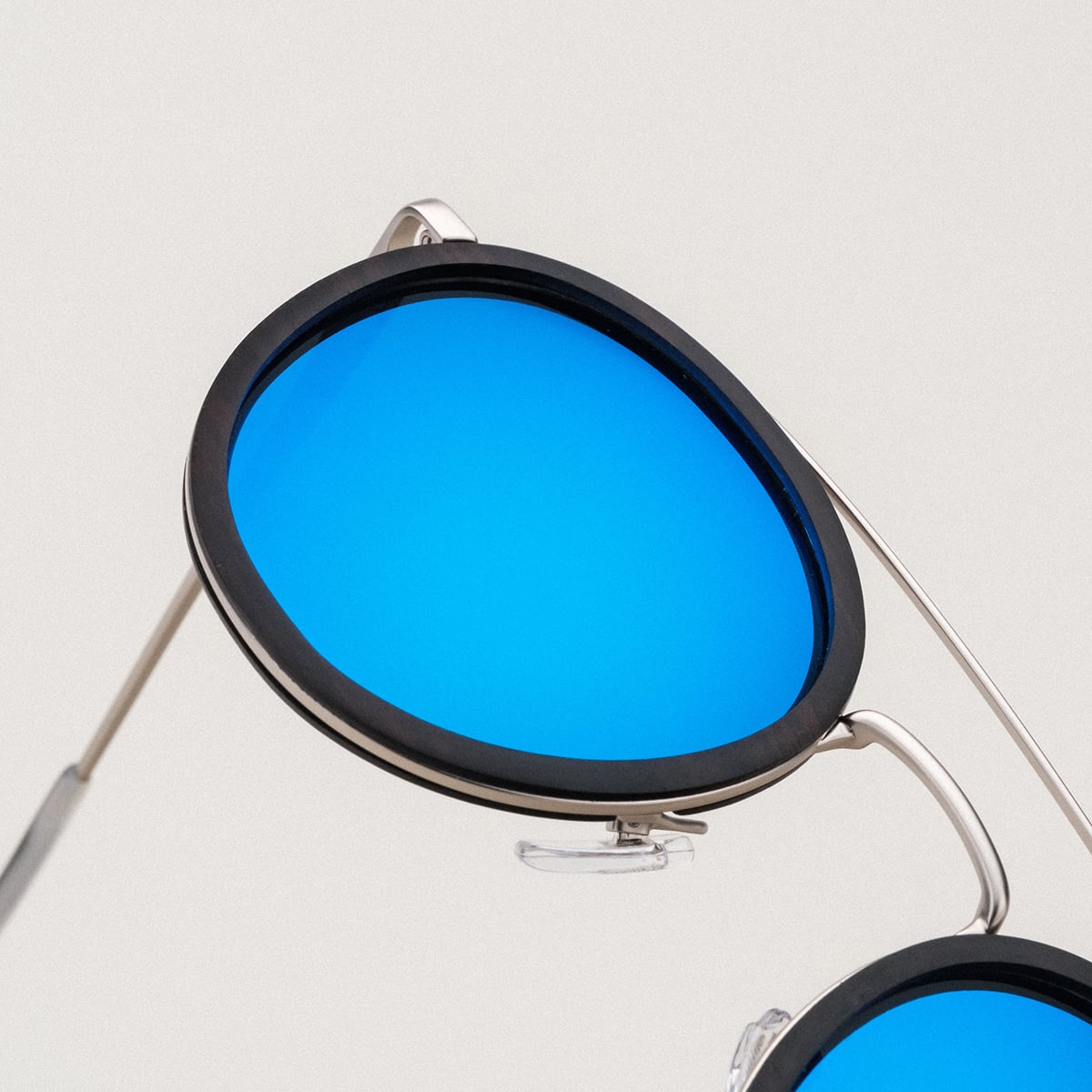 Occhiali da sole "Incantanti" con lenti blu, cornice in legno di piombo elegante e dettagli in argento antico.