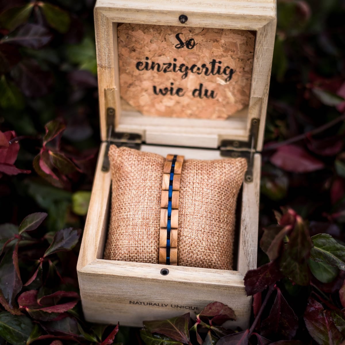Bracciale "Fantasia", realizzato in legno di ulivo e accenti blu, elegantemente esposto in una scatola di legno rustico.