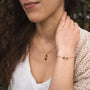 Bracciale "Mosaic" con un design in noce e oro a mosaico, indossato sul polso di una donna, completa un outfit casual.