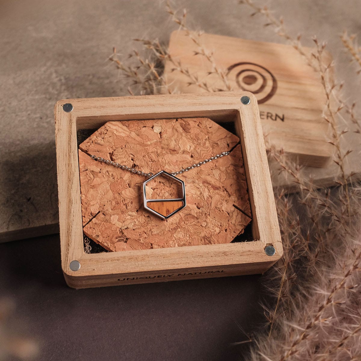 "Assemblage Necklace" features a geometric necklace design crafted from koa wood and silver, presented in a stylish wooden box.