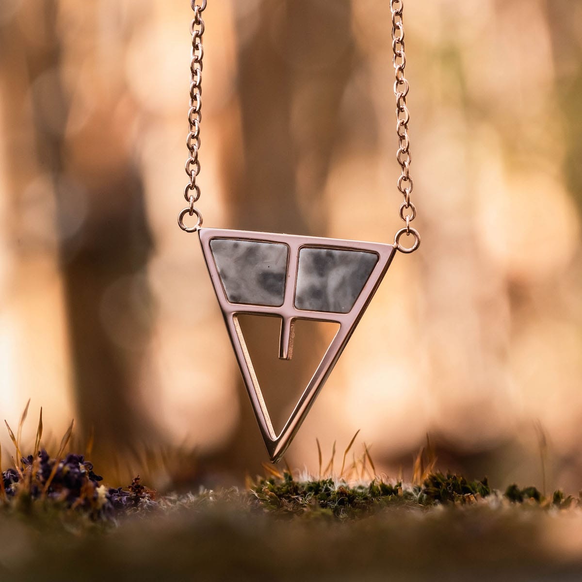 "Chiaroscuro Necklace necklace, featuring gray marble and rose gold in a geometric design against a soft-focus background."