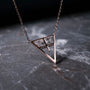"Chiaroscuro Necklace: A geometric necklace in gray marble and rose gold, featuring a striking triangular design."