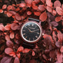 Orologio "Passion" con materiali Padauk e Maple, con un design classico ambientato sullo sfondo di vivaci foglie rosse.