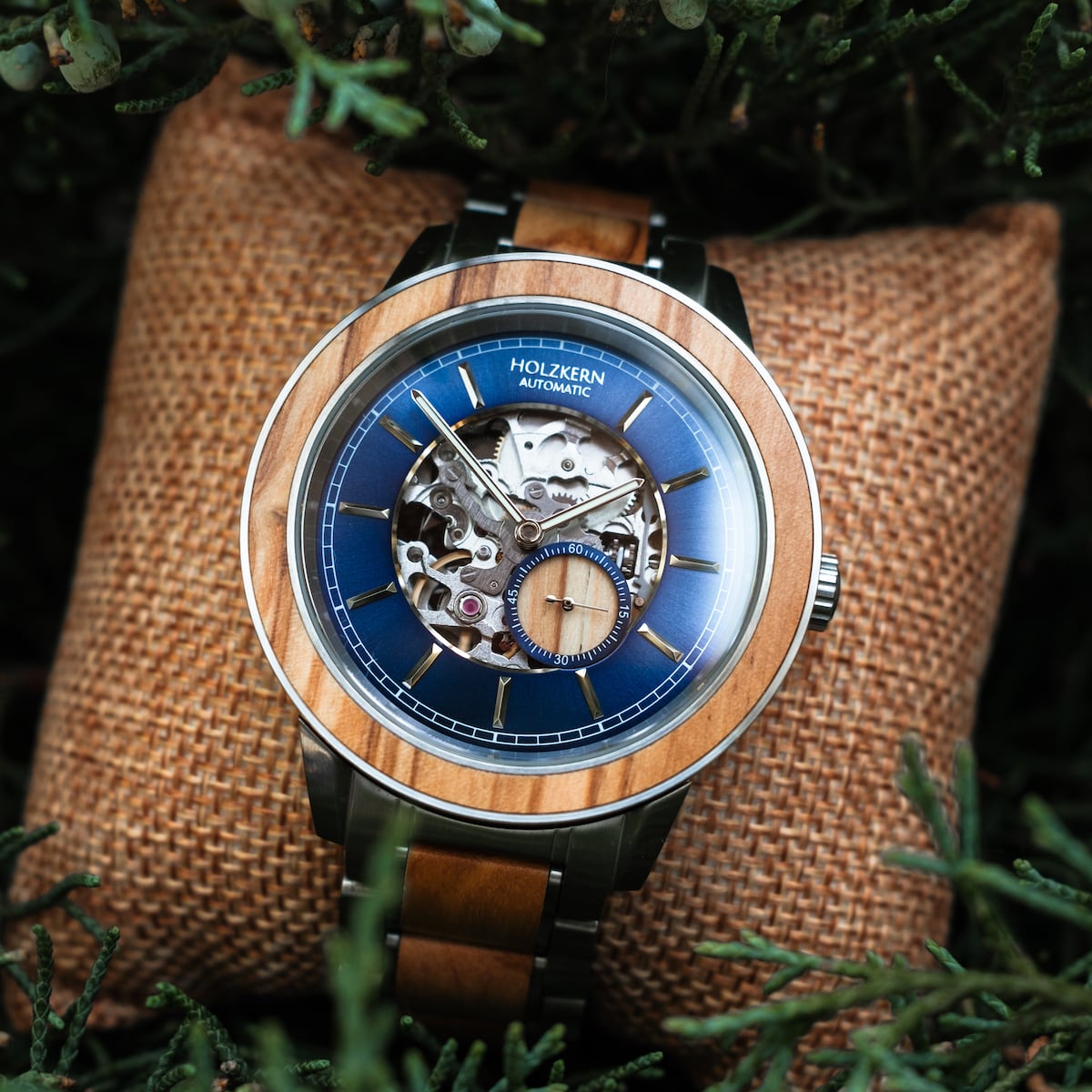 "Haiku" watch with automatic movement, featuring an olive-toned design and intricate details, set against a woven cushion.
