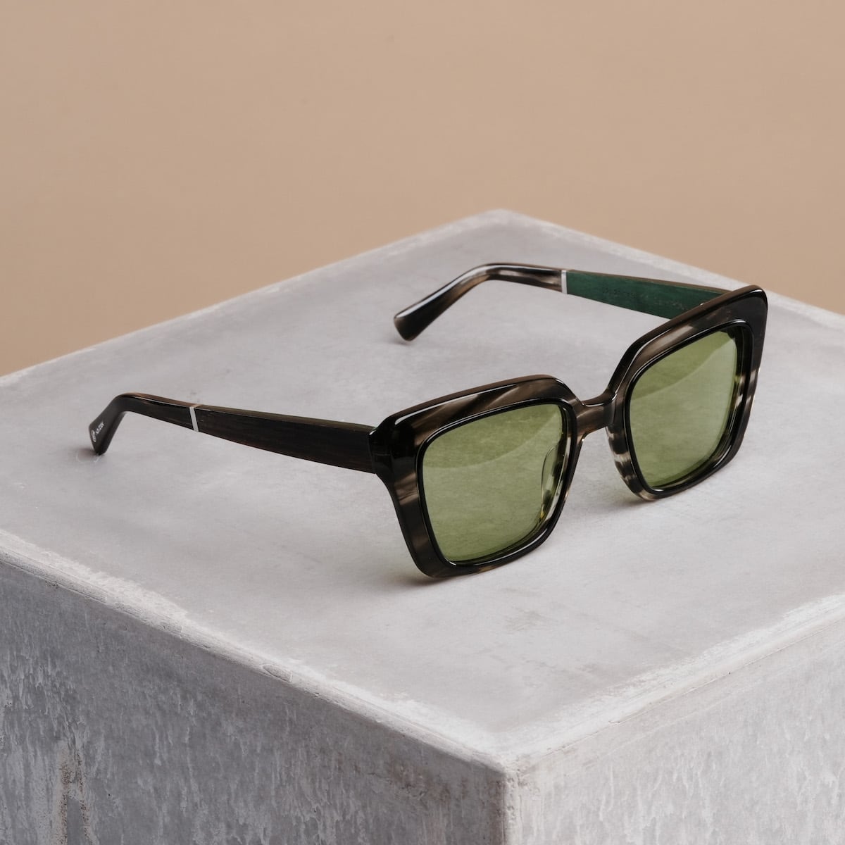 "The Exquisite sunglasses feature a classic square frame with a stylish Leadwood finish and Khaki Dust lenses on a neutral backdrop."