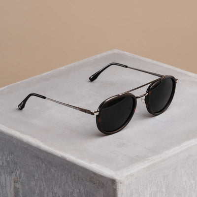 "The Risky" sunglasses with a sleek, round design in Leadwood and Antique Silver tones.