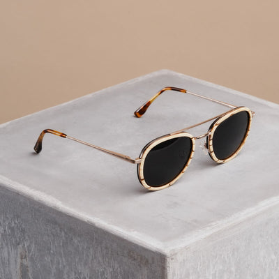 "The Risky" sunglasses featuring zebrawood arms and matte gold accents in a sleek design.