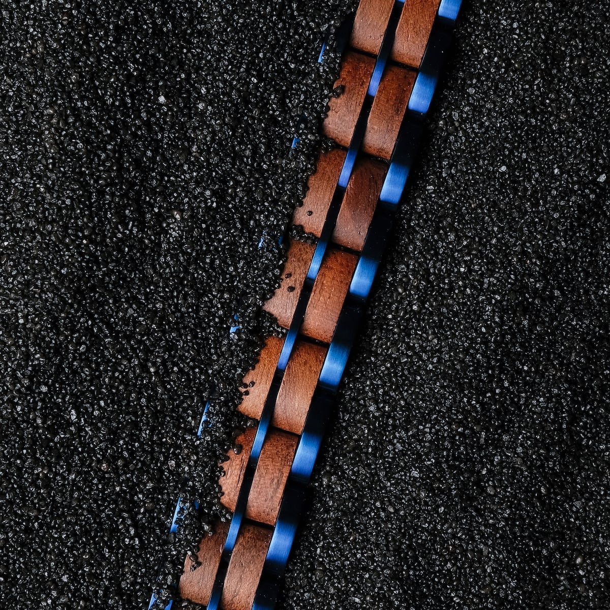 "Kanon" watch with walnut wood and blue accents on a textured black background.