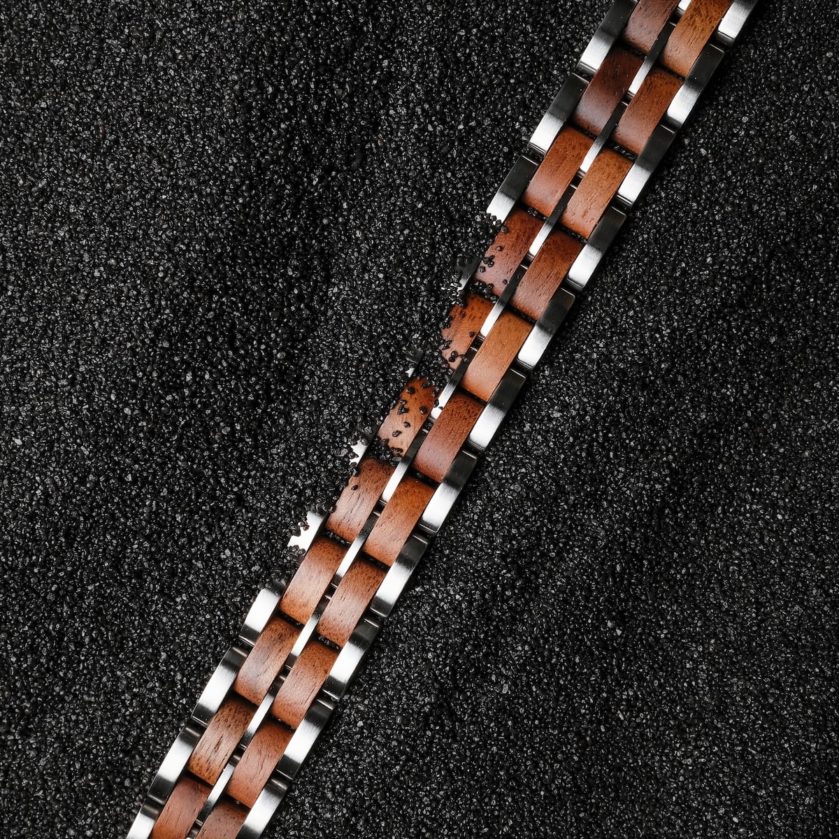 "Kanon", a bracelet, featuring a sleek walnut and silver design on a textured dark background.