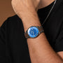 "Milestones watch featuring a sleek blue dial with a walnut-accented metal band, worn on a wrist for a stylish look."