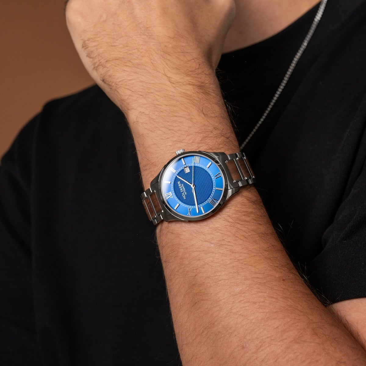 "Milestones watch featuring a sleek blue dial with a walnut-accented metal band, worn on a wrist for a stylish look."