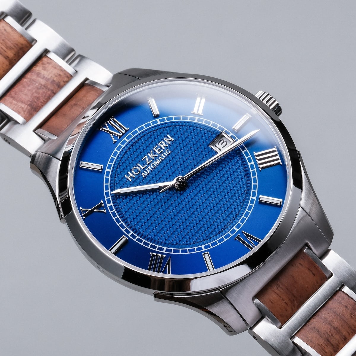 "Milestones watch with walnut accents, featuring a distinctive blue dial and stainless steel design."