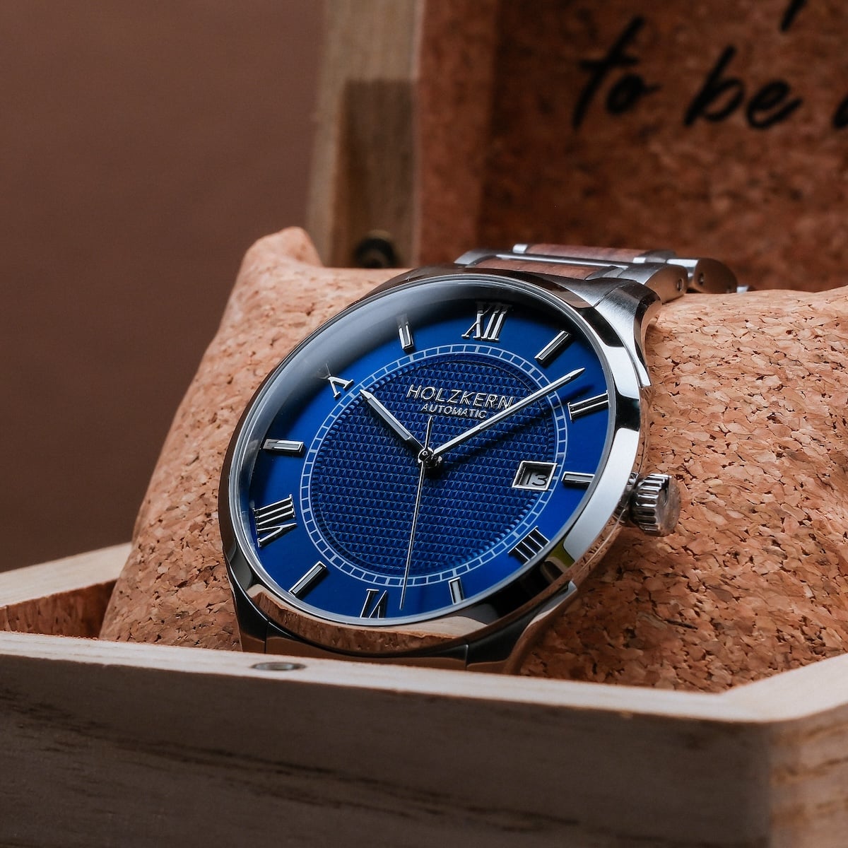 "Milestones watch featuring a walnut and blue design with Roman numerals and a sleek, modern style."