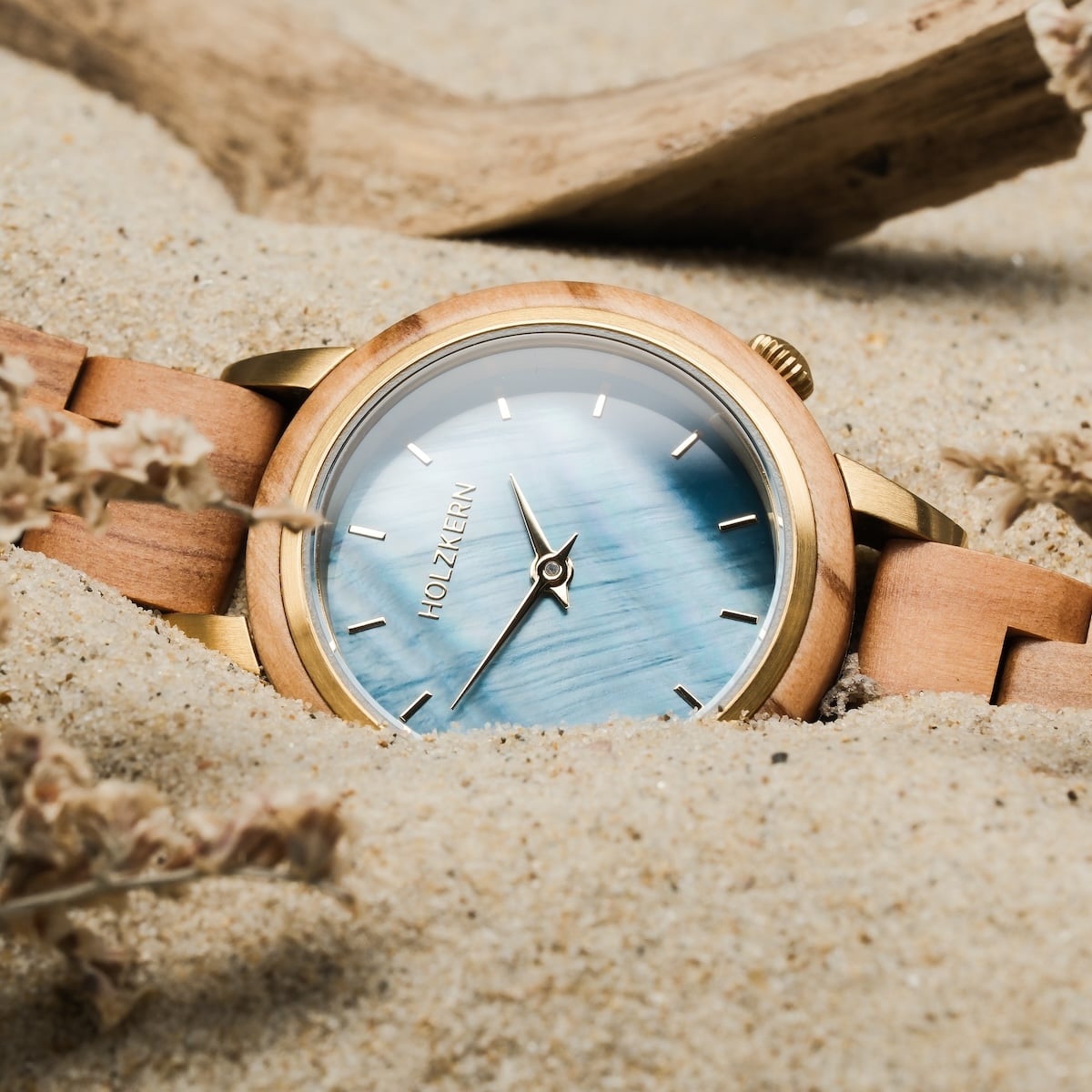 Orologio "Antrim" con una fascia in legno di tinta unita e un volto in stile nacre in una spiaggia di sabbia.