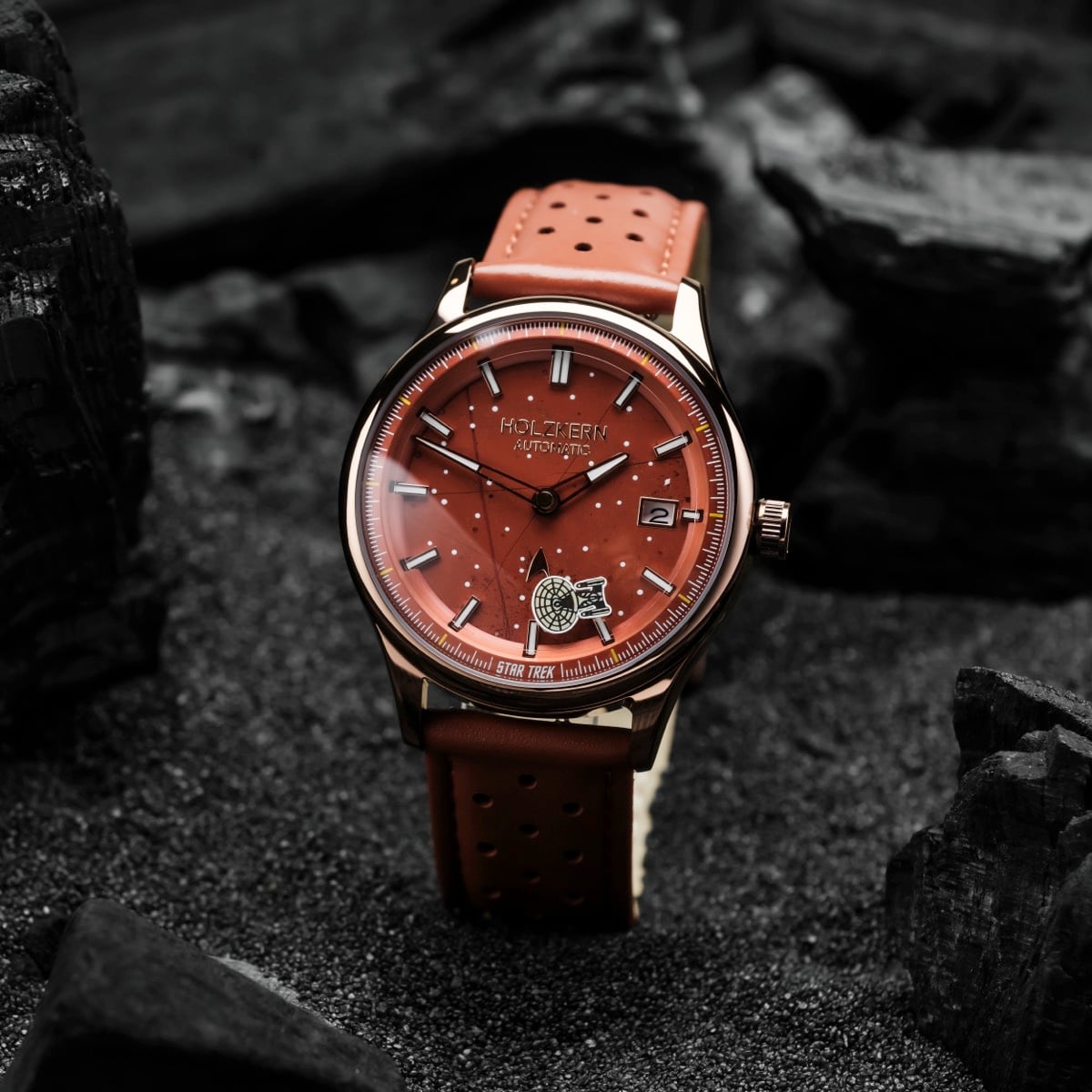 Orologio "NCC-1701-D" con quadrante rosso e cinturino, con design elegante e moderno su uno sfondo scuro texture.