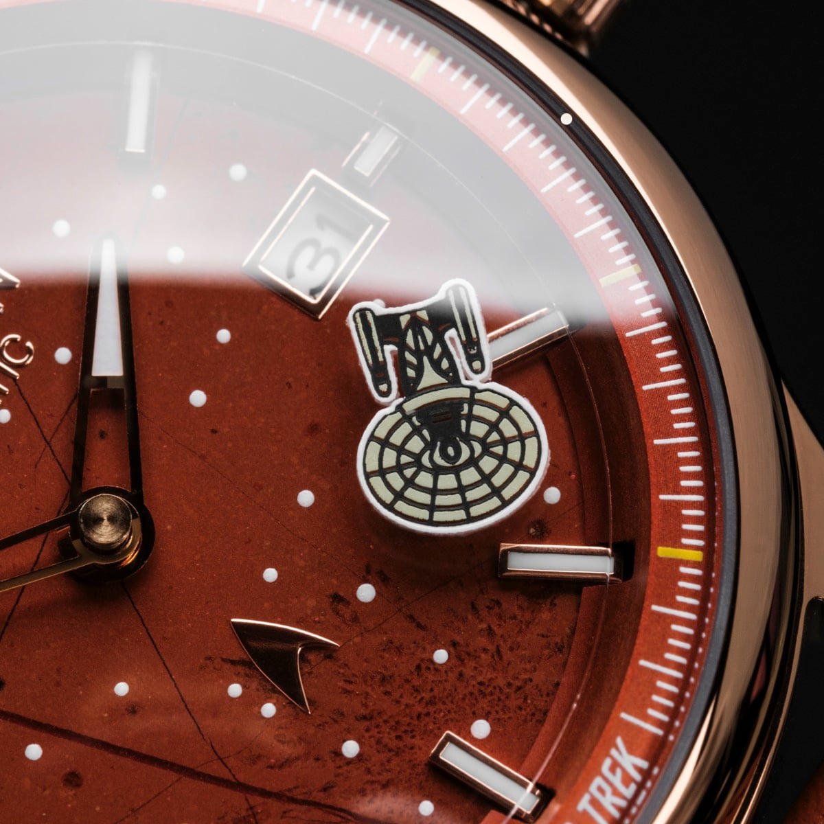 "NCC-1701-D", un orologio con un design rosso e rame, con elementi a tema spaziale e un aspetto elegante.