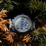 "Intergalactic watch featuring a marble face and leadwood accents, nestled among pine branches."