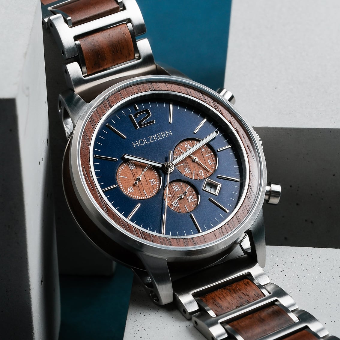 Orologio "Oscar" dal design in noce e blu, fondendo legno e metallo con un'estetica moderna.